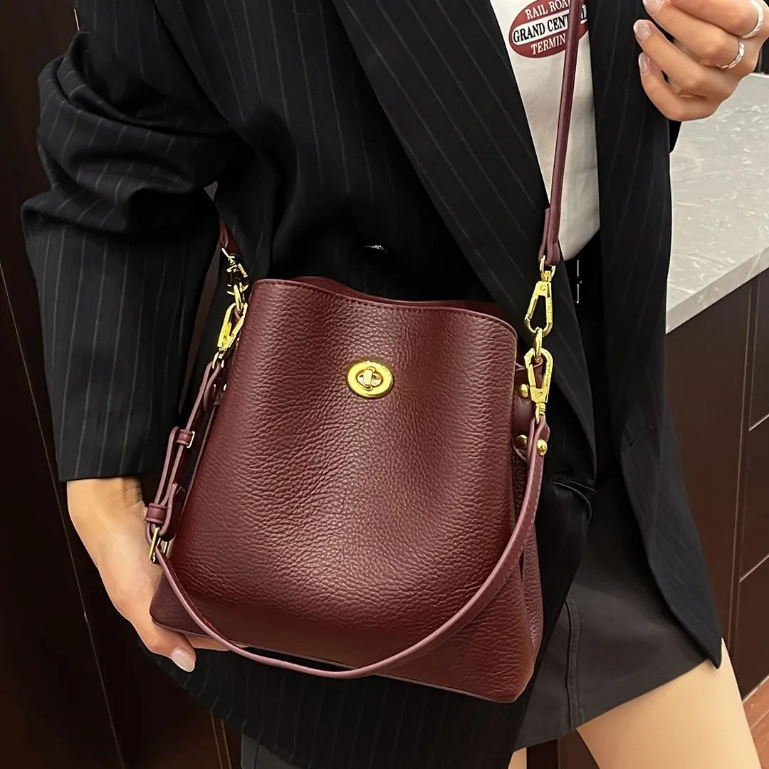 Elegant burgundy PU leather handbag for women, large capacity bucket shoulder bag with stylish design and spacious interior.