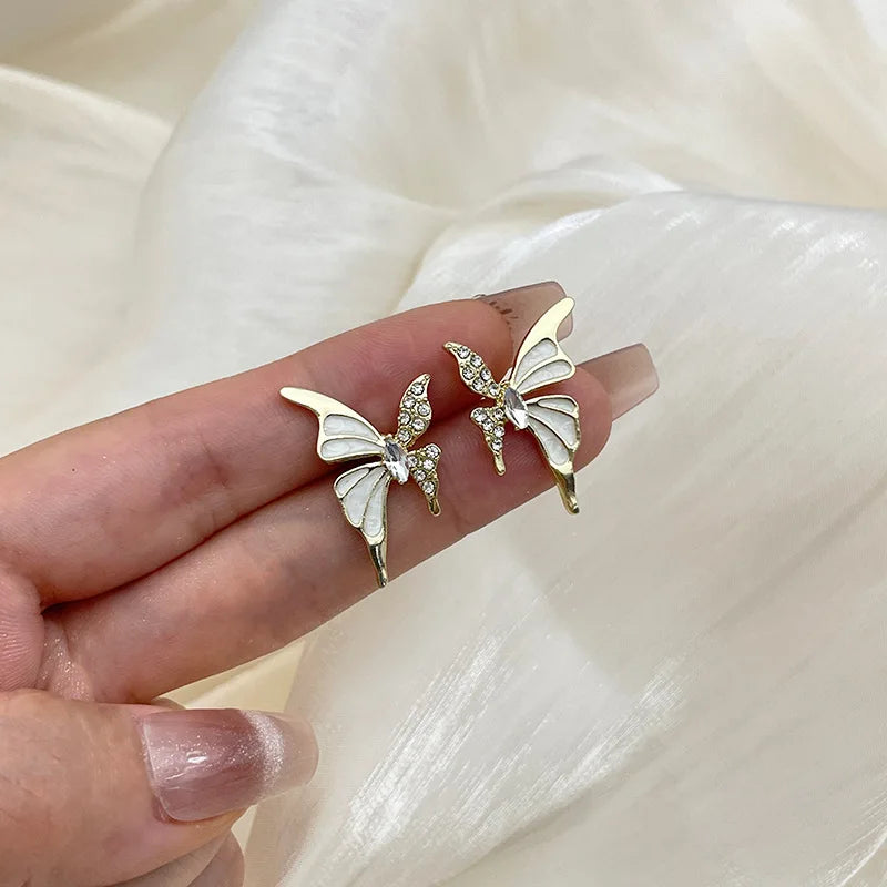 White enamel butterfly stud earrings with crystal wings in golden color metal for women