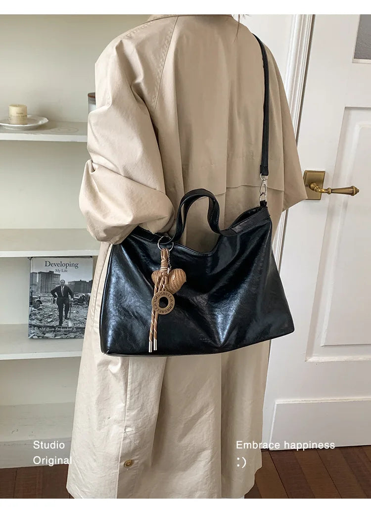 Luxury black PU leather women's handbag with spacious interior, shoulder strap, and stylish design for commuting and office use.