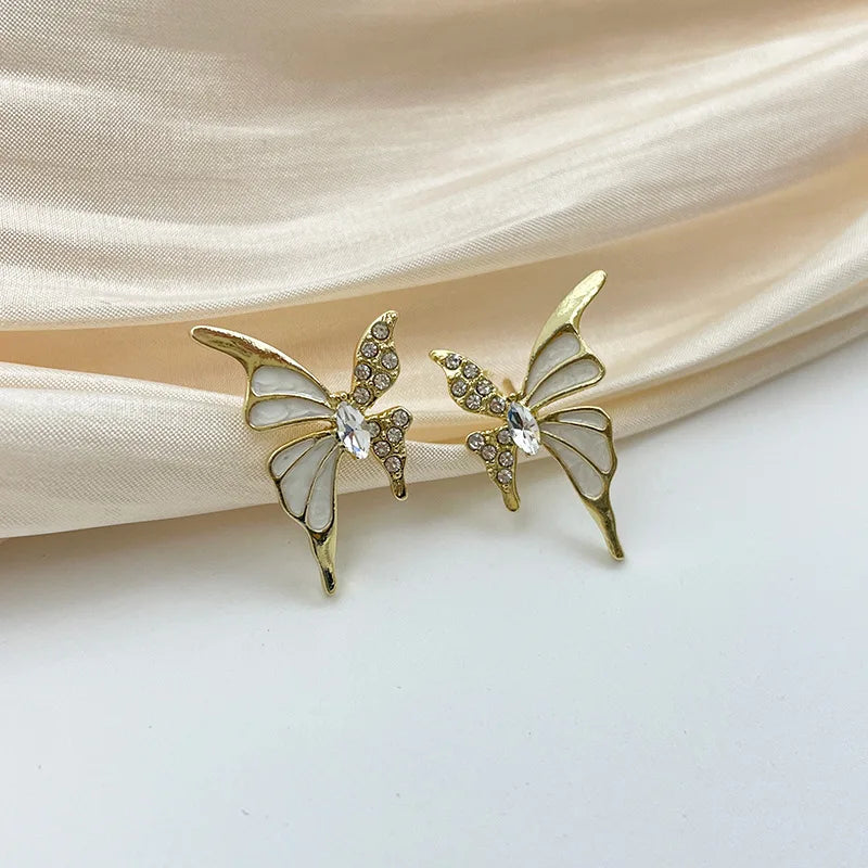 White enamel butterfly stud earrings with crystal wings in golden color metal for women