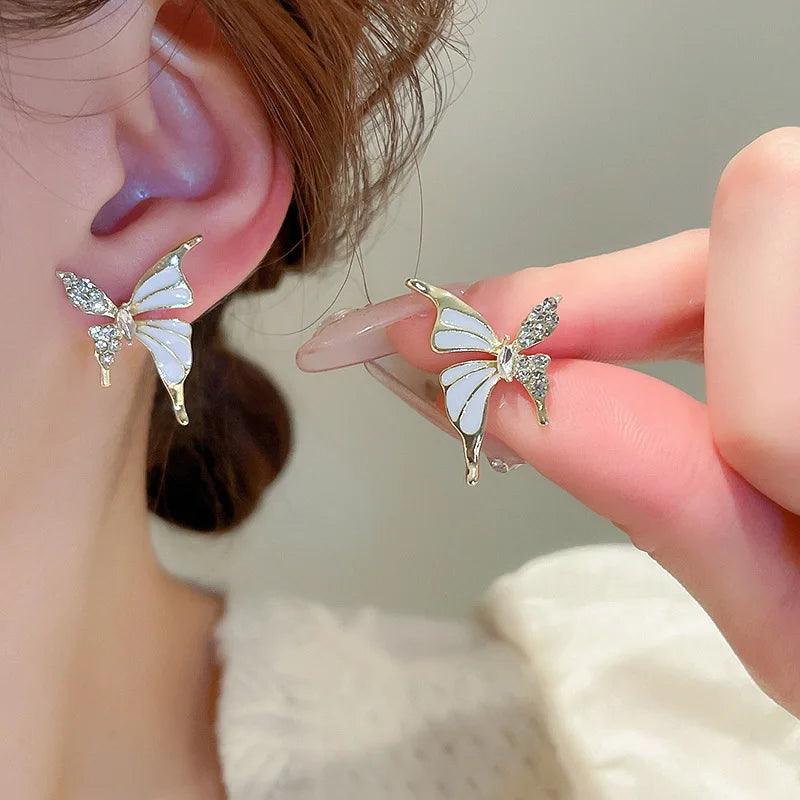 Cute butterfly stud earrings with white enamel, crystal wings, and golden color metal for women