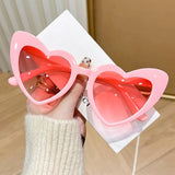 Pink heart-shaped vintage sunglasses from HSF Marketplace with shiny, transparent frames perfect for beach parties and photos.