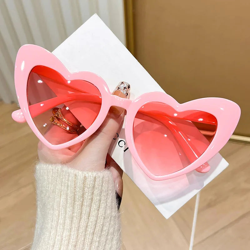 Pink heart-shaped vintage sunglasses from HSF Marketplace with shiny, transparent frames perfect for beach parties and photos.