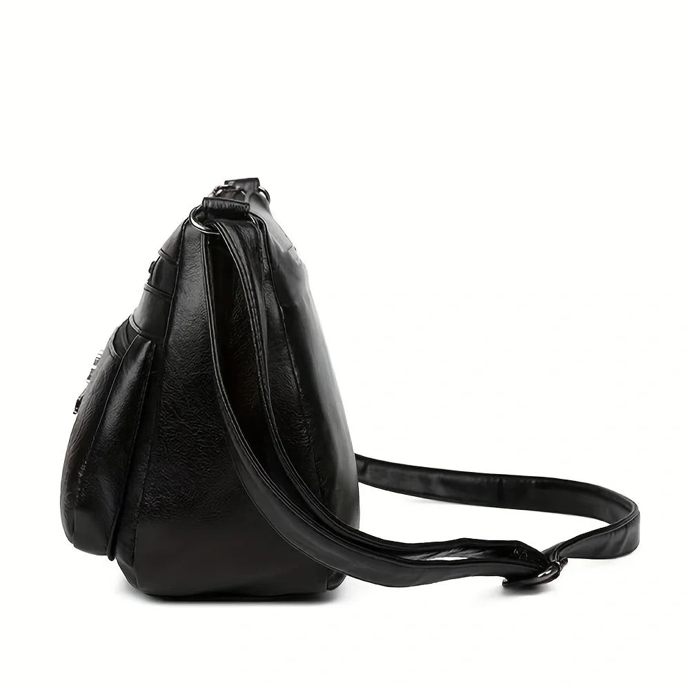 Black leather crossbody handbag with embossed design, featuring multiple pockets and a spacious interior, ideal for outings and parties.