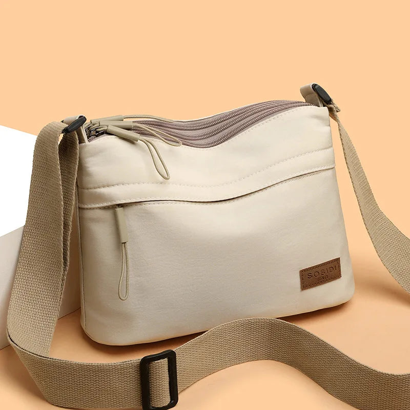 High capacity canvas shoulder crossbody bag for women with three main pockets, suitable for mothers and shopping.