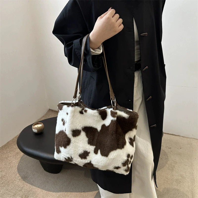 Large capacity women's winter shopper tote bag with cow print plush shoulder design, ideal for travel and everyday use.
