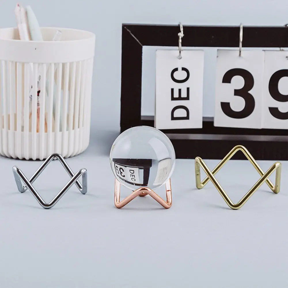 Glass sphere holder with metal crystal ball base, geometric design, ideal for photography props and home decoration.