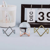 Glass sphere holder with metal crystal ball base, geometric design, ideal for photography props and home decoration.