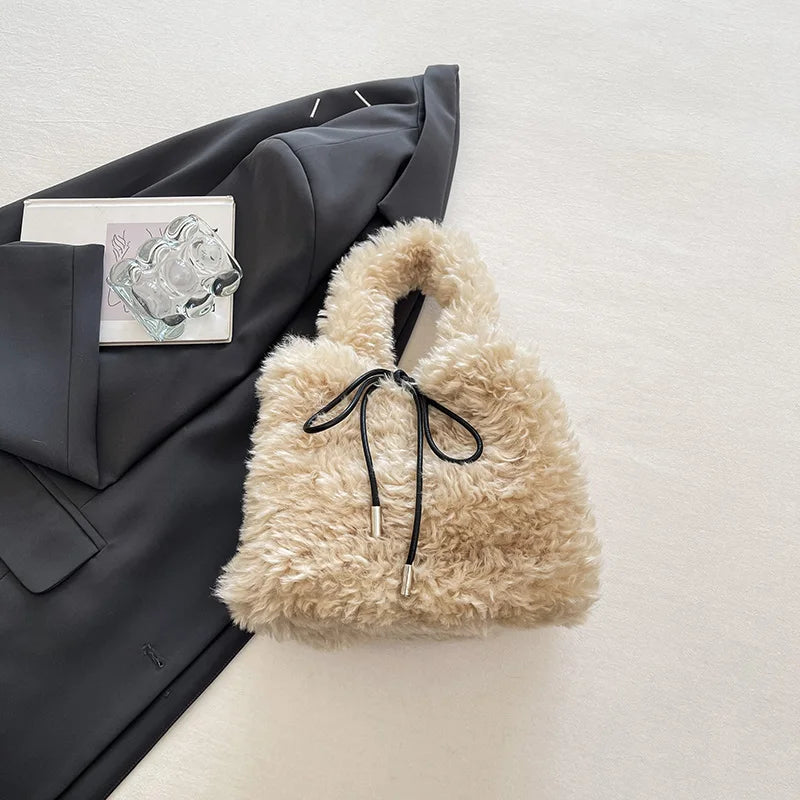 Left-side view of a 2026 winter faux fur small tote bag by HSF Marketplace with curly fluffy fur, drawstring top handle, and shoulder strap.