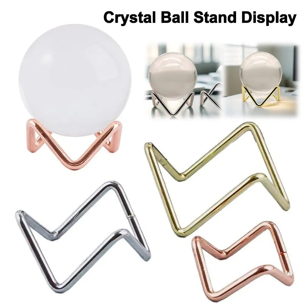Glass sphere holder with geometric metal base for crystal stones, used as a photography prop or home decoration.
