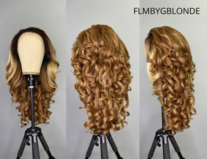 Glamorous golden-blonde curly synthetic lace front wig displayed on a tripod stand.